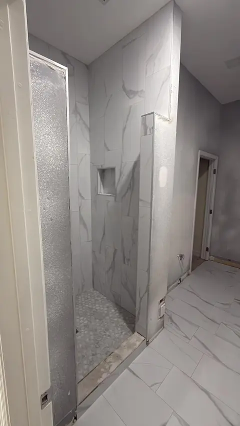 After: finished walk-in shower with marble-look porcelain wall tile, a recessed niche and a round mosaic floor
